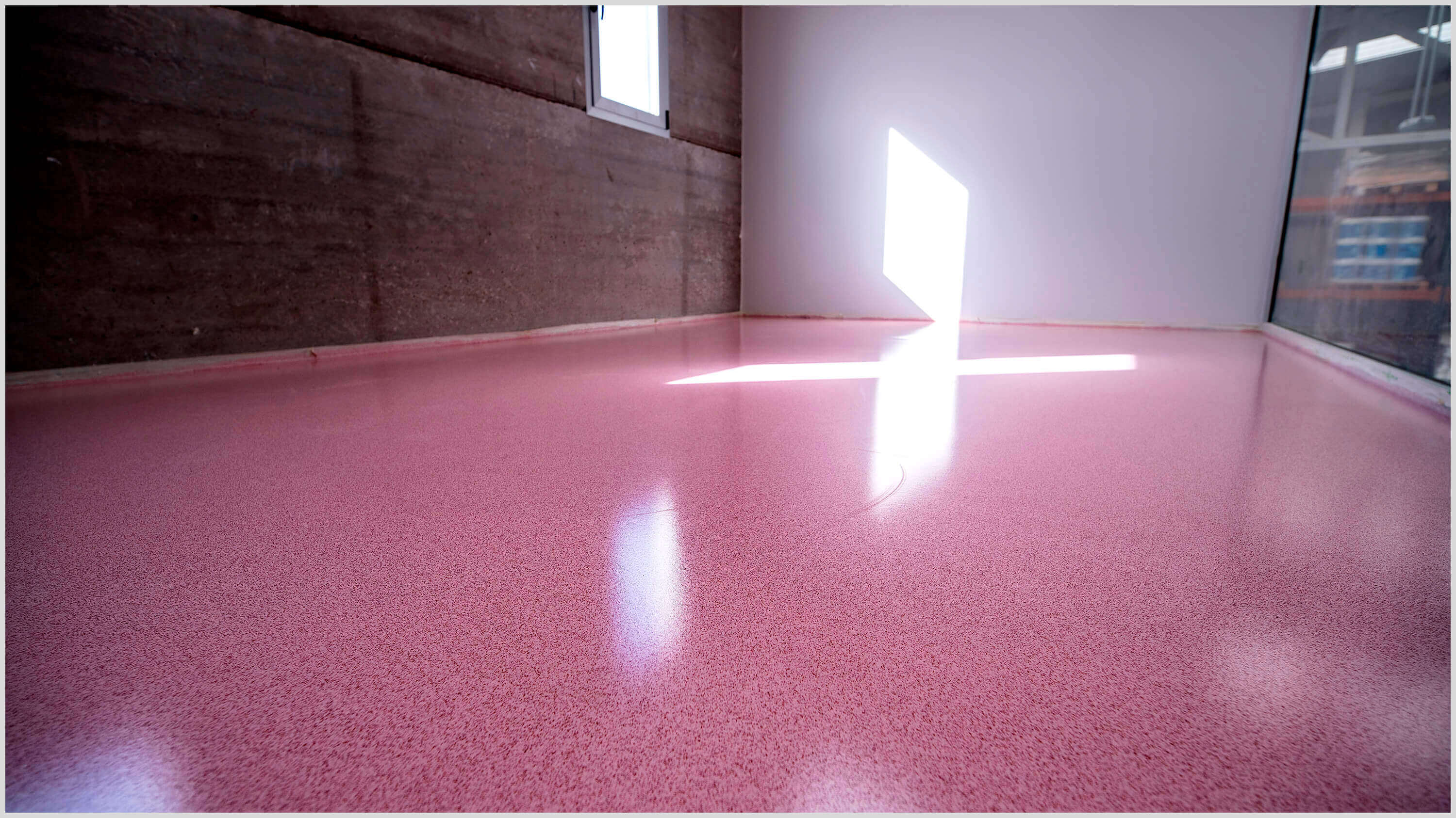 Pink seamless flooring in a room with concrete walls and natural light