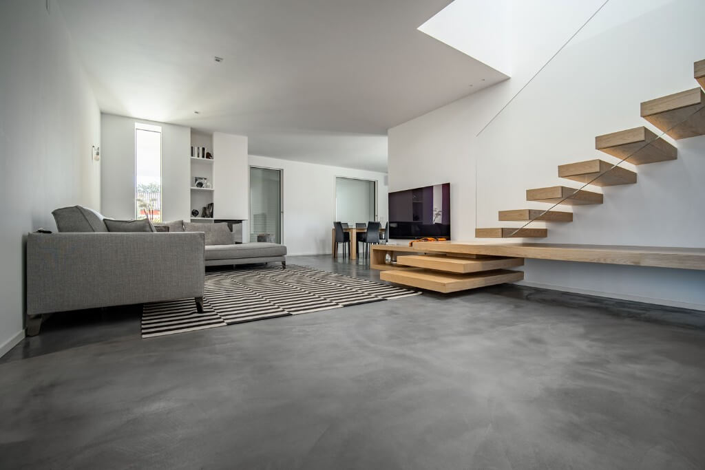 Suelo continuo gris en un salón con escalera de madera