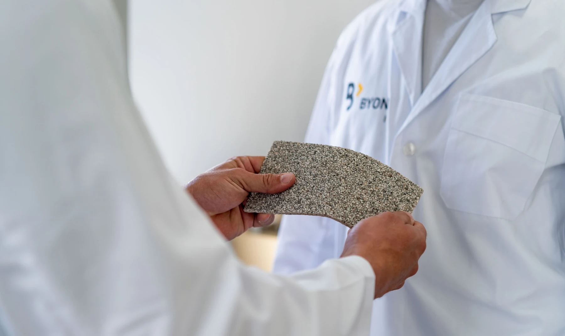 Una muestra de pavimento Zoruflex sostenida por un miembro del equipo de laboratorio de BYOND